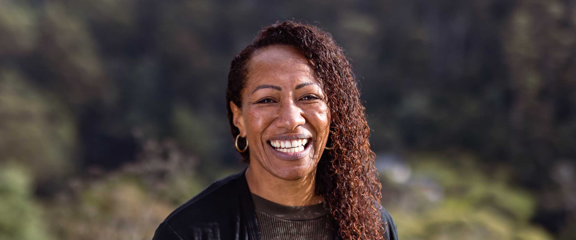 An early childhood educator standing outside and smiling.