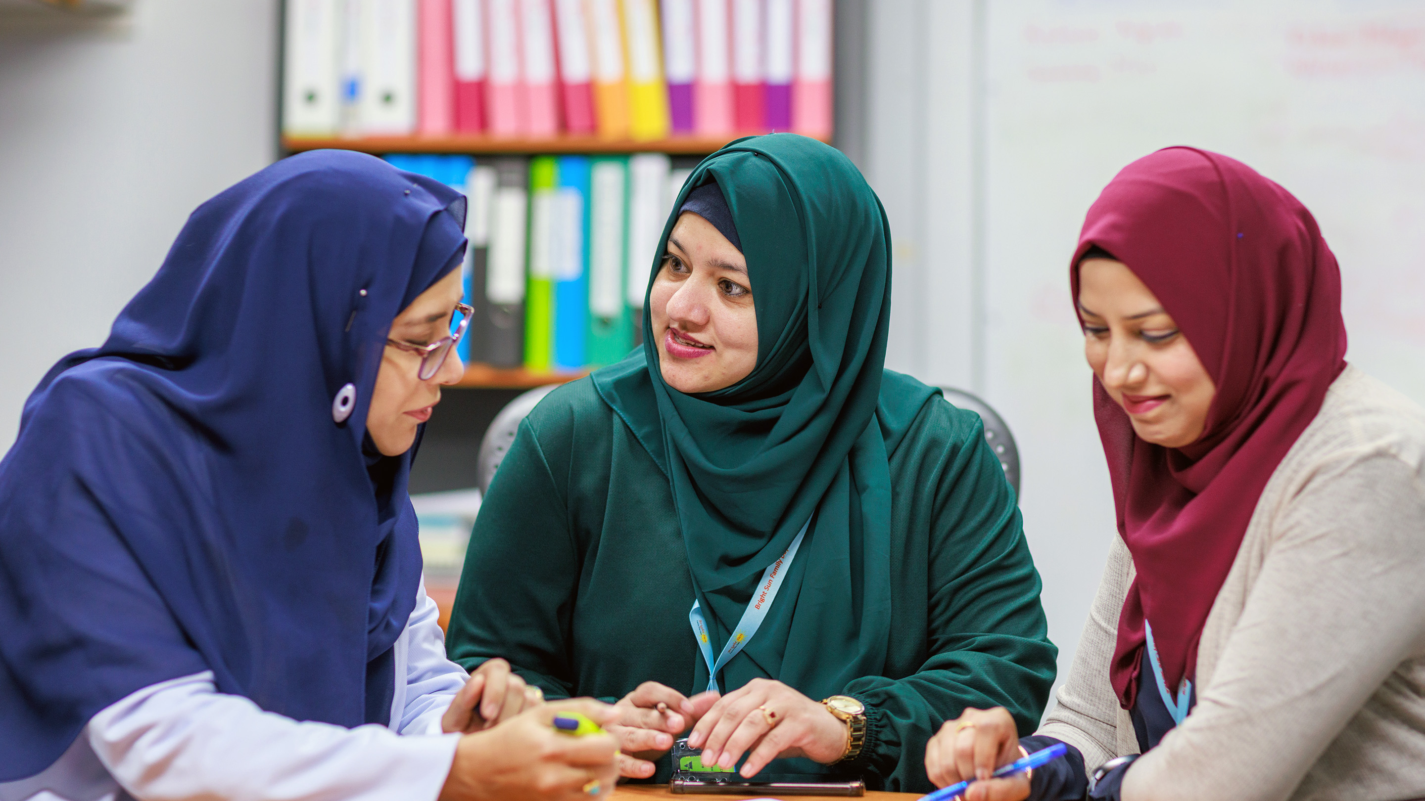 Three educators sitting around a table and talking to each other.