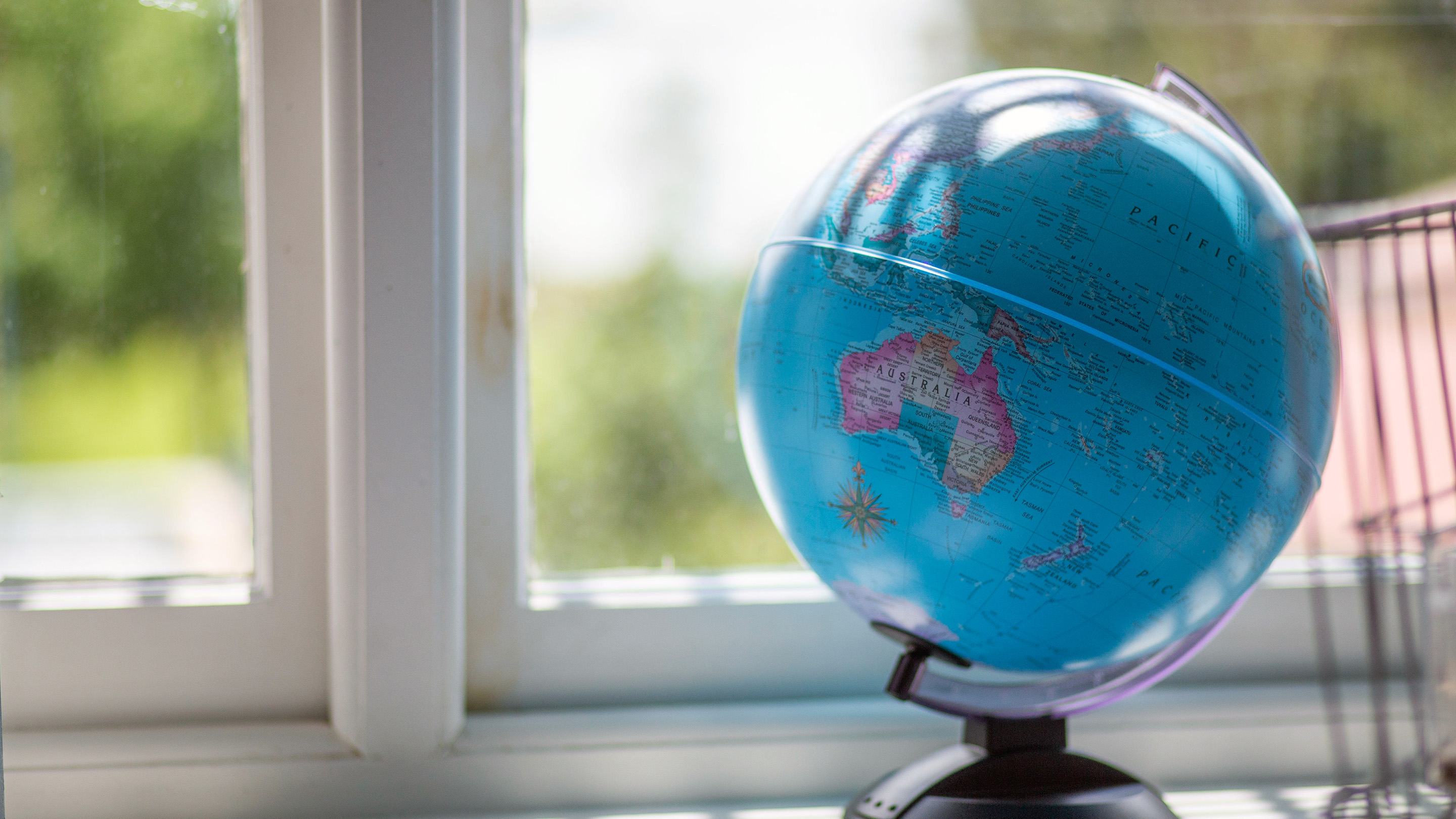 A globe of the world on a window sill.