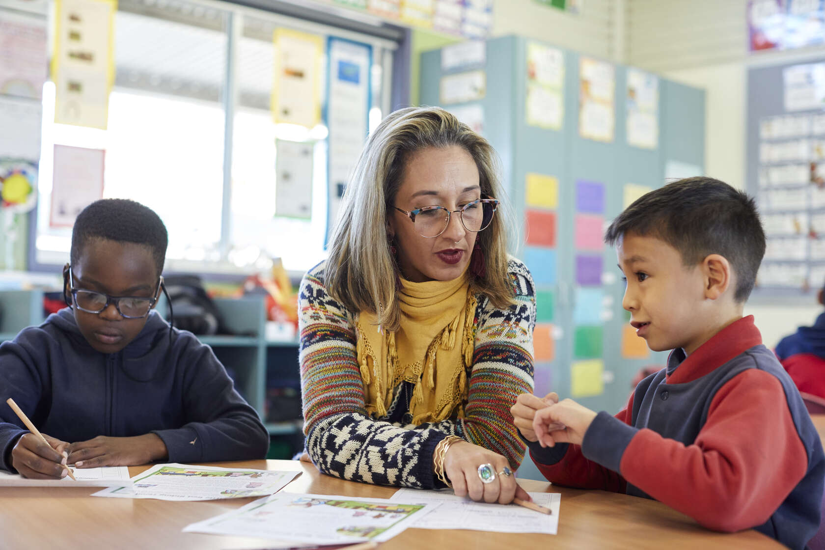 An educator sitting with children, helping with schoolwork    